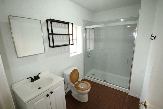 bathroom with toilet, a shower stall, wood finished floors, and vanity