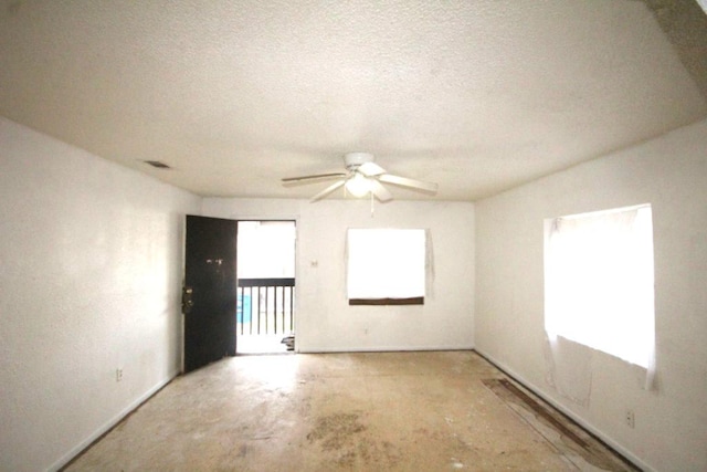 spare room with a textured ceiling, plenty of natural light, visible vents, and a ceiling fan