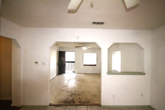 unfurnished room featuring visible vents, concrete floors, a textured ceiling, and a ceiling fan