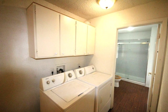 clothes washing area with dark wood-style floors, washer and dryer, cabinet space, and a textured ceiling