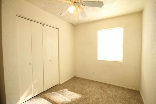 unfurnished bedroom with a closet, carpet flooring, ceiling fan, and a textured ceiling