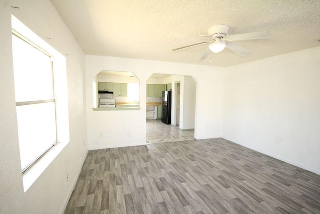 5204 Guadalupe St, Austin, TX 78751 - unfurnished living room with arched walkways, wood finished floors, a ceiling fan, and a textured ceiling