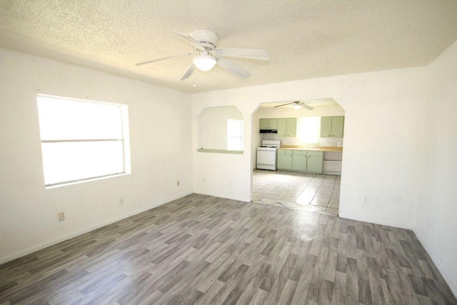 5204 Guadalupe St, Austin, TX 78751 - unfurnished living room with ceiling fan, light wood finished floors, a textured ceiling, and arched walkways