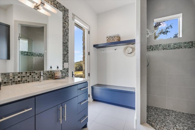 bathroom featuring decorative backsplash, tile patterned flooring, vanity, and a tile shower