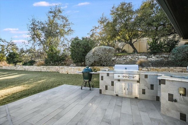 view of patio / terrace featuring exterior kitchen, area for grilling, fence, and a wooden deck