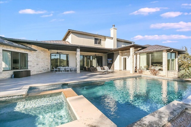 back of property featuring a patio, a standing seam roof, outdoor dining area, stone siding, and metal roof