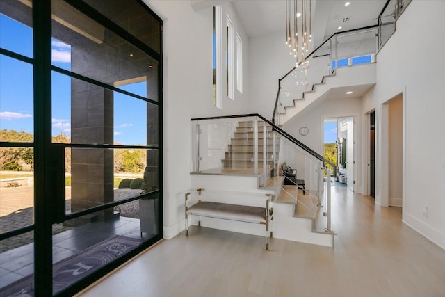 entryway featuring stairway, wood finished floors, baseboards, a high ceiling, and expansive windows