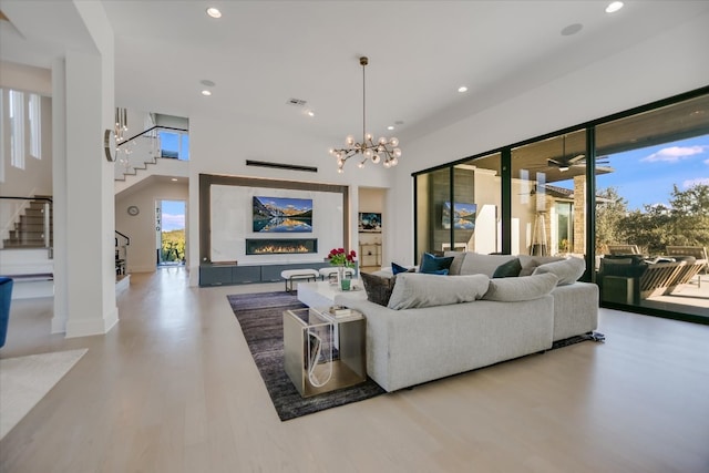 living area featuring baseboards, stairway, recessed lighting, a high ceiling, and wood finished floors