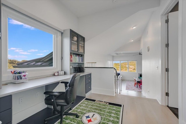 home office with baseboards, built in study area, lofted ceiling, and wood finished floors