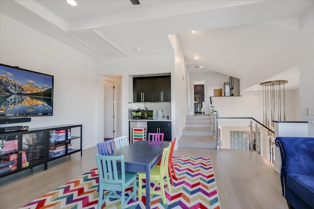 dining space featuring vaulted ceiling, attic access, recessed lighting, and wood finished floors