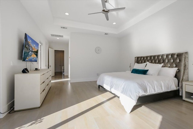 bedroom featuring recessed lighting, a tray ceiling, visible vents, and light wood finished floors