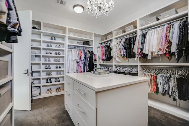 spacious closet with a notable chandelier, dark wood-style floors, and visible vents