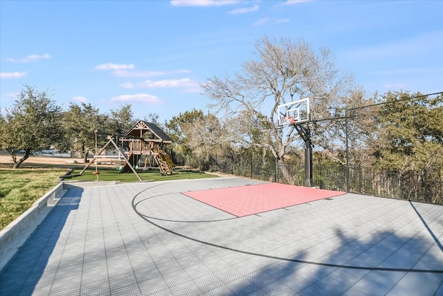 view of basketball court with basketball hoop, a playground, and a yard