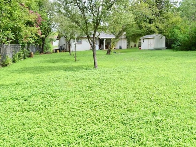 view of yard featuring a storage unit, an outdoor structure, and fence