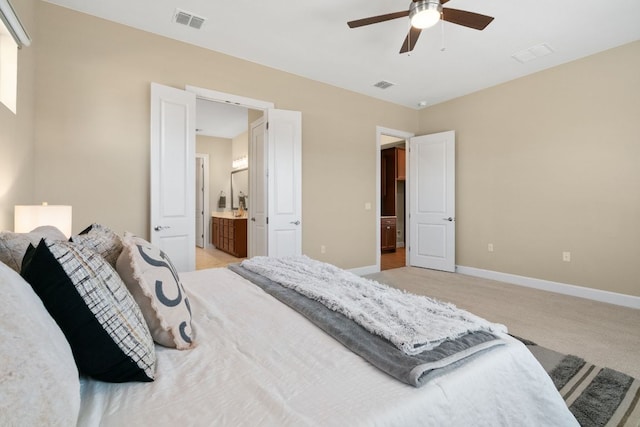 bedroom featuring light colored carpet, visible vents, ensuite bath, and baseboards