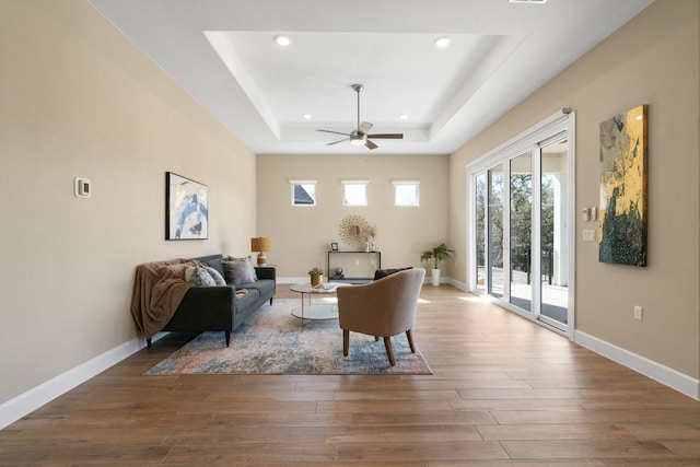 living room featuring recessed lighting, a raised ceiling, a ceiling fan, wood finished floors, and baseboards