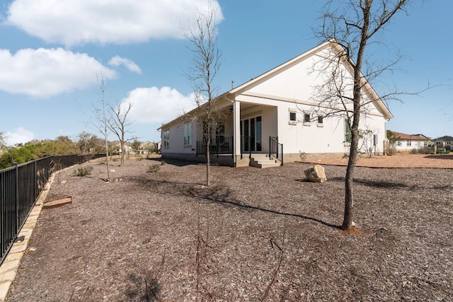 back of house featuring fence and stucco siding