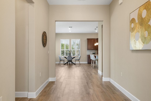 corridor with wood finished floors, visible vents, and baseboards