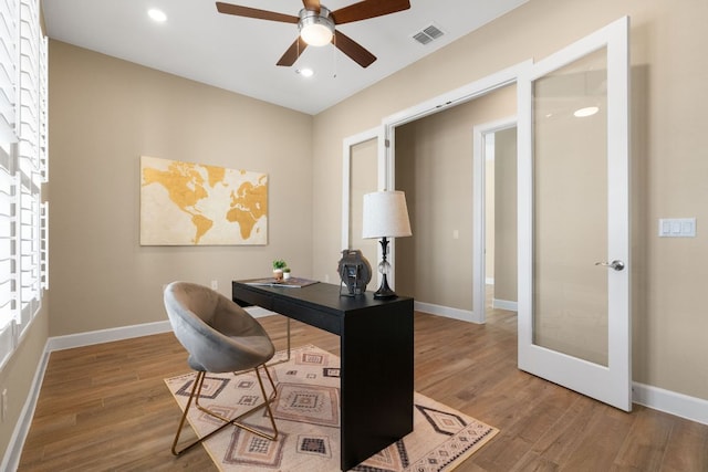 office featuring ceiling fan, wood finished floors, visible vents, and baseboards