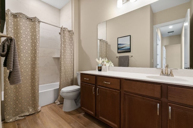 bathroom with visible vents, toilet, shower / bath combo, vanity, and wood finished floors