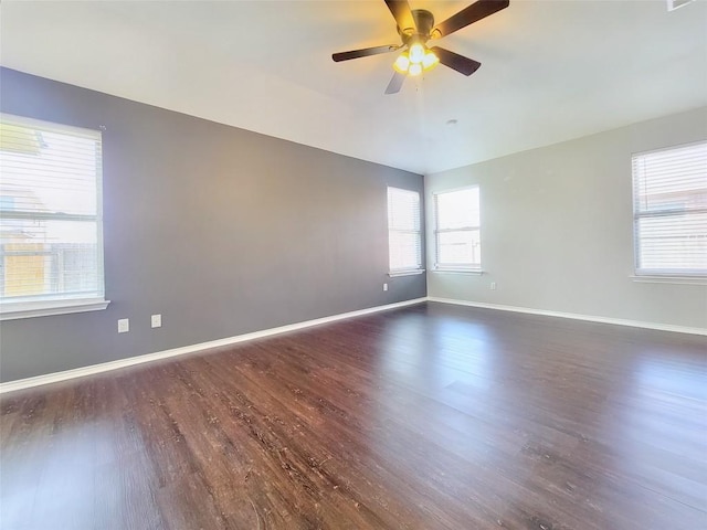 spare room with a ceiling fan, dark wood finished floors, and baseboards