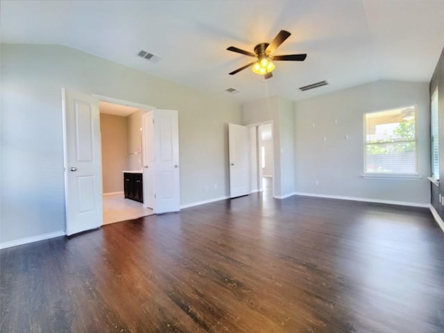 spare room featuring visible vents, vaulted ceiling, and dark wood finished floors