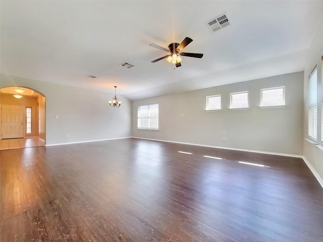 spare room featuring arched walkways, wood finished floors, visible vents, and baseboards