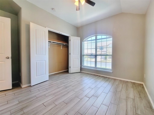 unfurnished bedroom with lofted ceiling, a ceiling fan, baseboards, light wood-style floors, and a closet