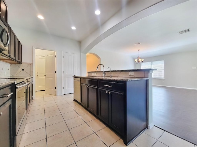 kitchen with arched walkways, tasteful backsplash, visible vents, appliances with stainless steel finishes, and a sink