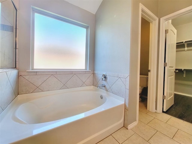 bathroom with toilet, a walk in closet, a bath, and tile patterned floors