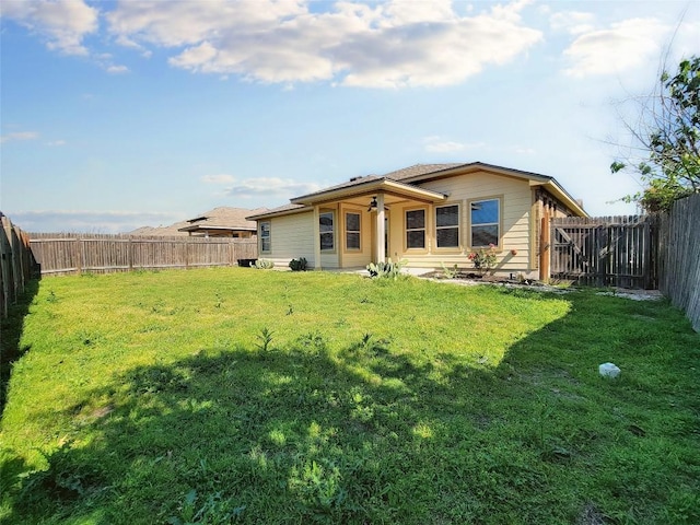 rear view of property with a lawn and a fenced backyard