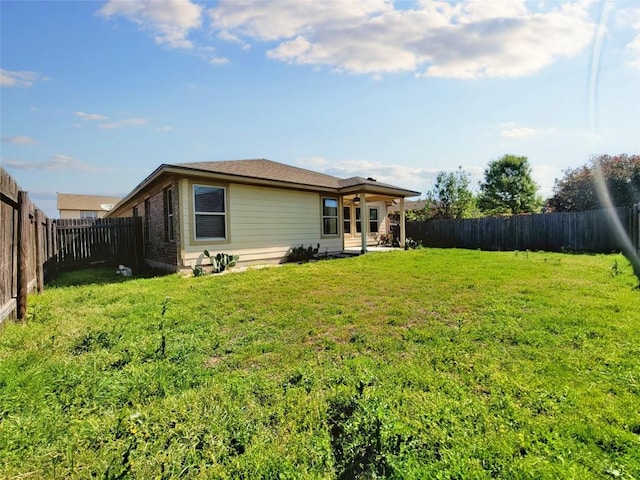 back of house featuring a lawn and a fenced backyard