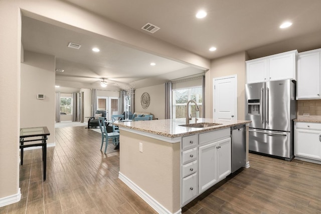 kitchen with a sink, open floor plan, appliances with stainless steel finishes, backsplash, and dark wood finished floors