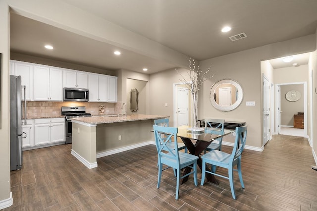 kitchen with stainless steel appliances, visible vents, a sink, and dark wood-style floors