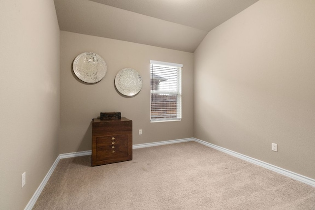 spare room with lofted ceiling, carpet floors, and baseboards