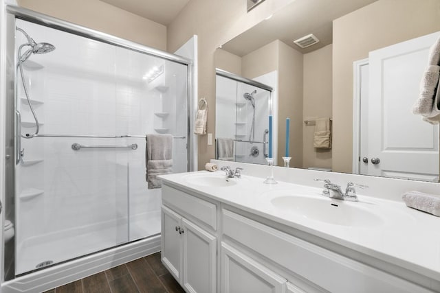 bathroom featuring a shower stall, visible vents, a sink, and wood finished floors