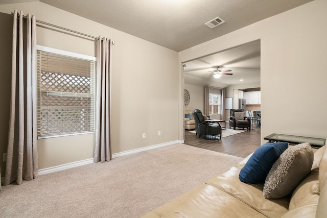 living room with a ceiling fan, carpet, visible vents, and baseboards