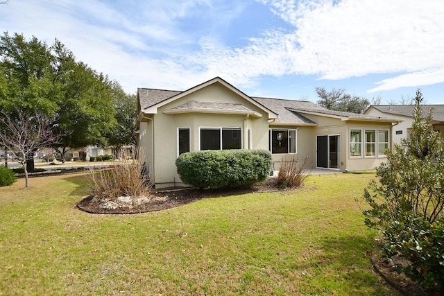 rear view of house featuring a yard and stucco siding