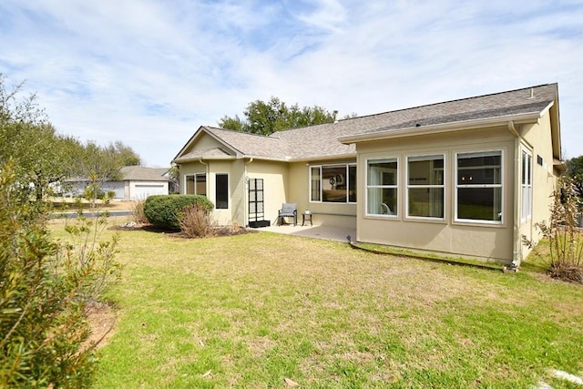 back of property with a garage, stucco siding, a lawn, and a patio