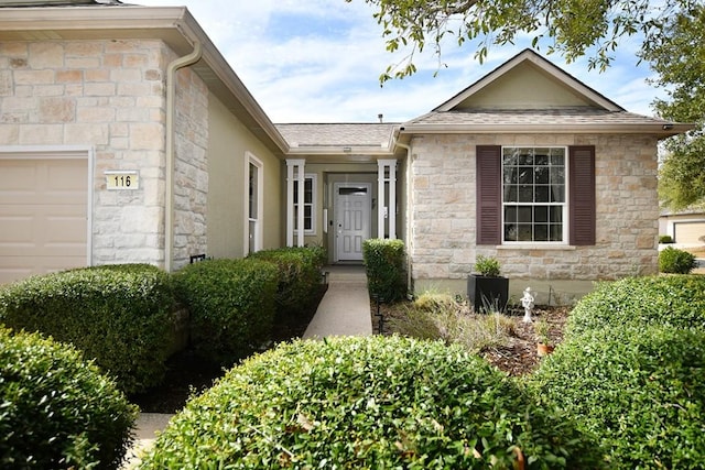 view of front of home featuring stone siding, roof with shingles, and an attached garage