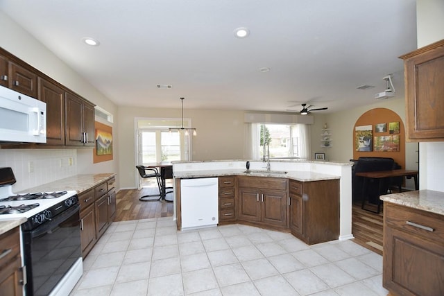 kitchen with ceiling fan, light stone counters, white appliances, a sink, and backsplash