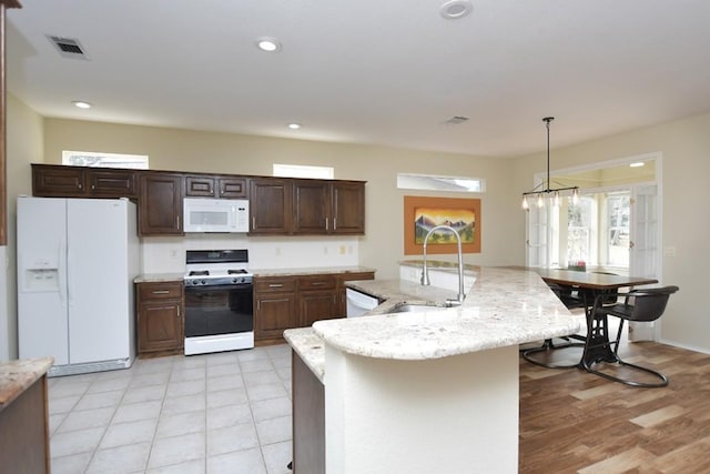 kitchen featuring recessed lighting, white appliances, visible vents, and a sink