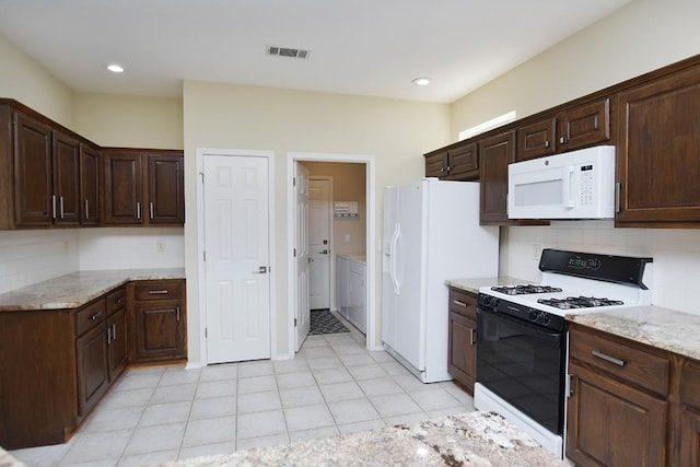 kitchen featuring white appliances, light stone countertops, visible vents, and tasteful backsplash