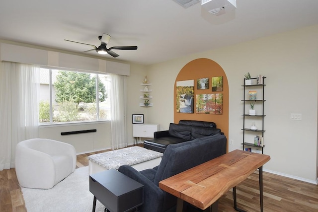 living area featuring ceiling fan, baseboards, and wood finished floors