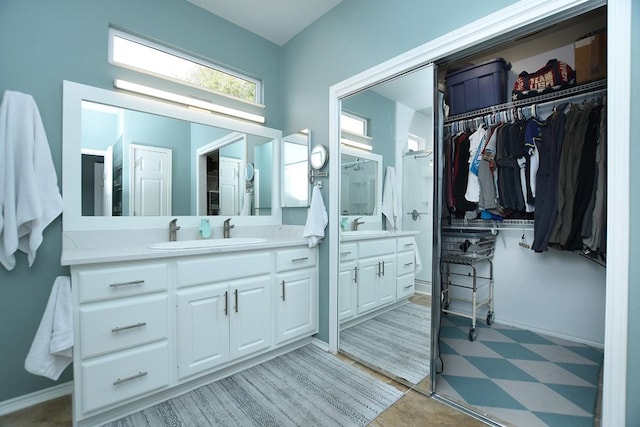 full bathroom featuring tile patterned floors, baseboards, a walk in closet, and vanity