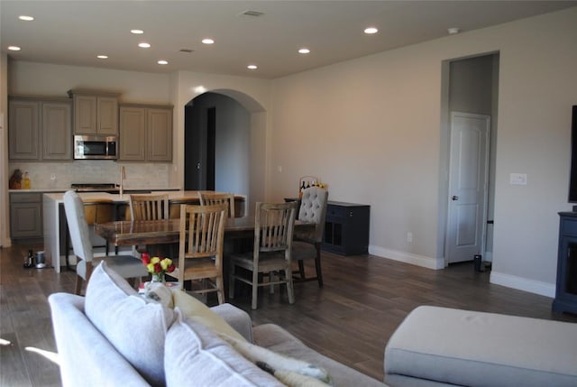 living area featuring dark wood-style floors, arched walkways, and recessed lighting