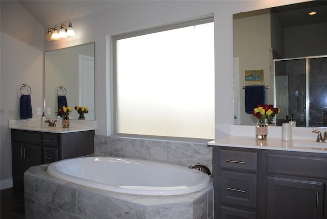 bathroom featuring a stall shower, vanity, and a bath