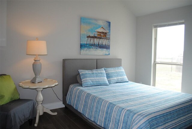 bedroom featuring lofted ceiling, wood finished floors, and baseboards