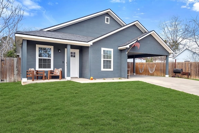 view of front facade featuring a front lawn, fence, covered porch, concrete driveway, and a carport