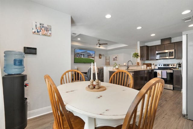 dining area featuring visible vents, baseboards, a tray ceiling, recessed lighting, and light wood-style floors